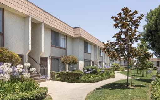 a row of apartments with gardens and trees in front of them
