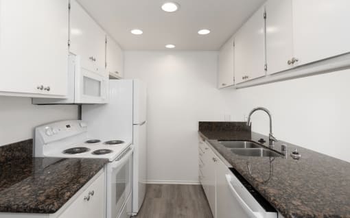 a kitchen with white appliances and granite counter tops and white cabinets