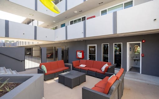 A modern outdoor seating area with red couches and grey planters.