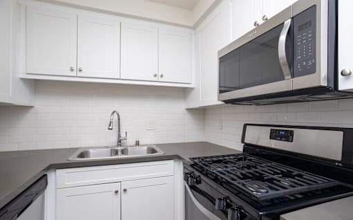 A modern kitchen with a black stove top oven and white cabinets.