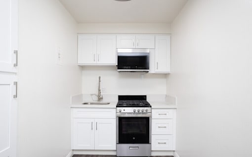 A white kitchen with a stove and microwave.