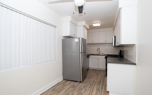 A kitchen with a refrigerator, sink, and cabinets.
