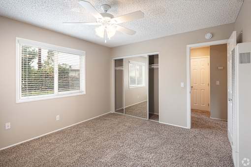 A room with a ceiling fan and a window with blinds.