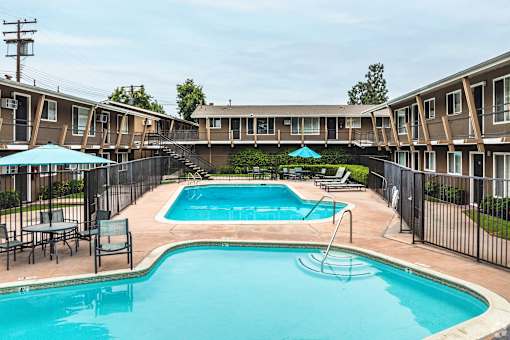 A swimming pool surrounded by a black fence and chairs.