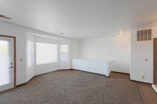 A large, empty room with a carpeted floor and white walls.
