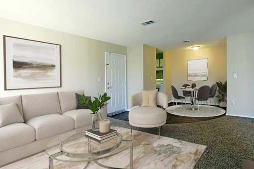 A living room with a white couch, a glass coffee table, and a painting on the wall.