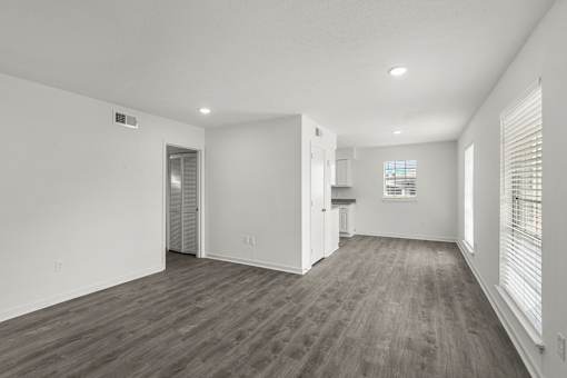 A spacious room with wooden flooring and white walls.