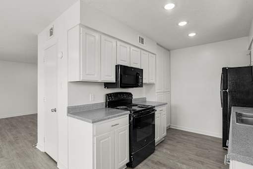 A kitchen with black appliances and white cabinets.
