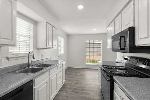 A kitchen with white cabinets and black appliances.