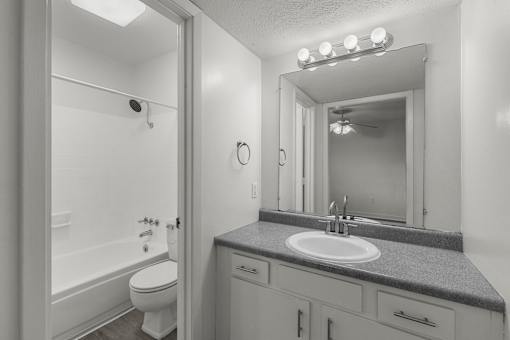 A bathroom with a toilet, sink, and mirror.