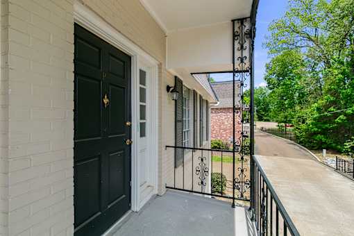 A black door with a gold handle is on a white brick house.
