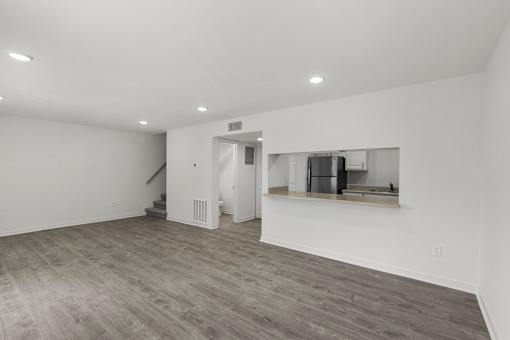 A spacious room with a staircase and a kitchenette.