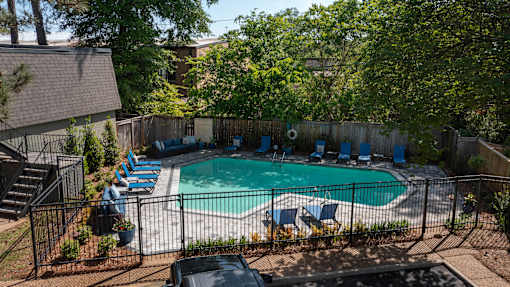 A backyard with a pool and lounge chairs.