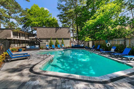 A large outdoor swimming pool surrounded by trees and deck chairs.