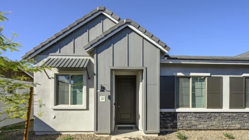a gray house with a black door and a blue sky at Village of Chandler Apartments, Arizona, 85249