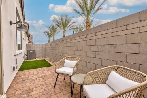 a patio with two chairs and a table next to a wall at Village of Chandler Apartments, Chandler, 85249