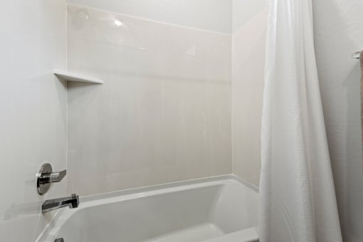 a bathroom with a tub and a shower curtain at Village of Chandler Apartments, Chandler, Arizona
