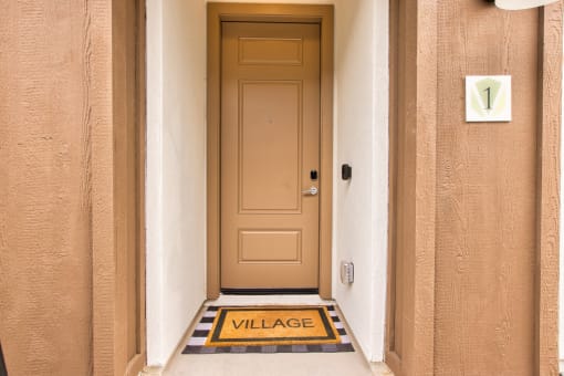the front door of a building with a door way with a sign that says village at Village of Chandler Apartments, Chandler, Arizona