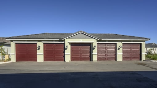 a garage with red doors in front of a house at Village of Chandler Apartments, Chandler