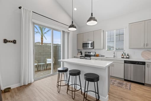 an open kitchen with a island and three stools at Village of Chandler Apartments, Chandler