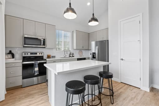 a kitchen with a large island with three stools at Village of Chandler Apartments, Chandler, AZ, 85249