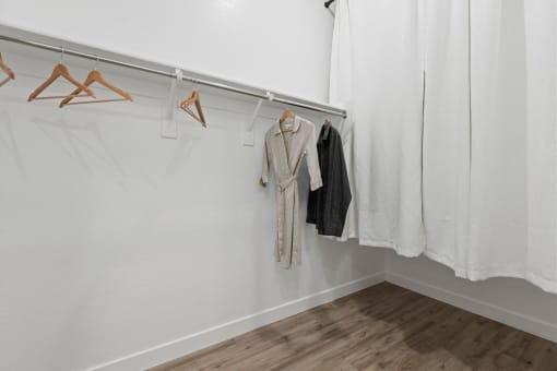 a white room with clothes hanging on a rack and a white curtain at Village of Chandler Apartments, Arizona