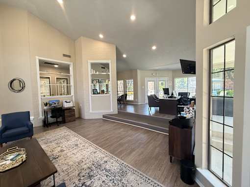 A spacious living room with a blue chair and a wooden coffee table.