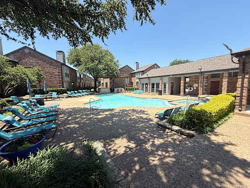 A pool surrounded by a patio with chairs and a hedge.