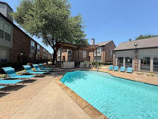 A swimming pool surrounded by lounge chairs and buildings.