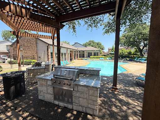 A BBQ grill is in the middle of a patio.