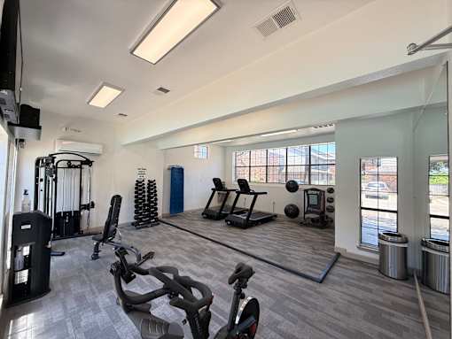 A gym with a variety of equipment including treadmills, weights, and exercise balls.