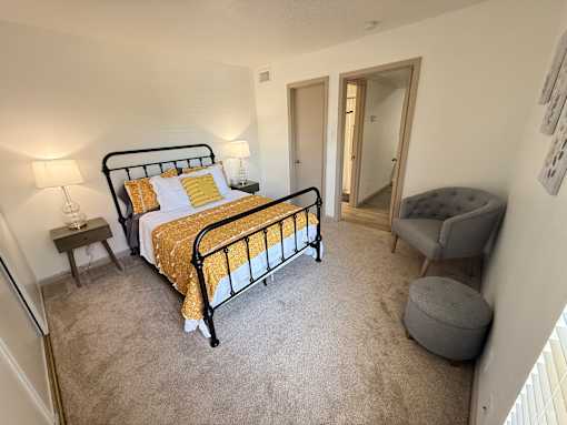 A bedroom with a bed, chair, and mirror.