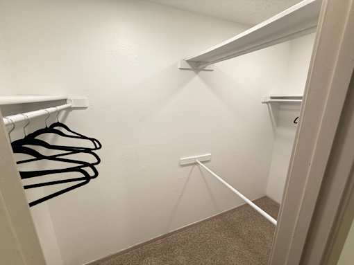 A white closet with a carpeted floor and a white door.