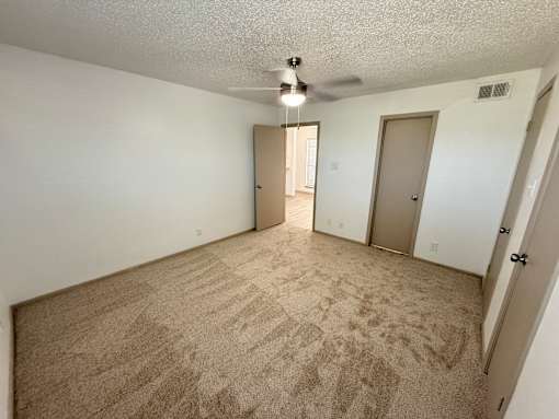 A room with a ceiling fan and carpeted floor.