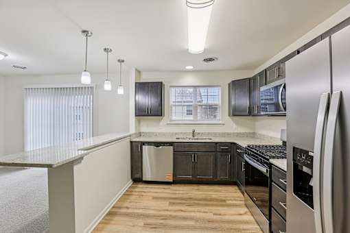 A modern kitchen with stainless steel appliances and wooden floors.
