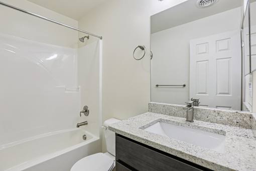A white bathroom with a toilet, sink, and shower.