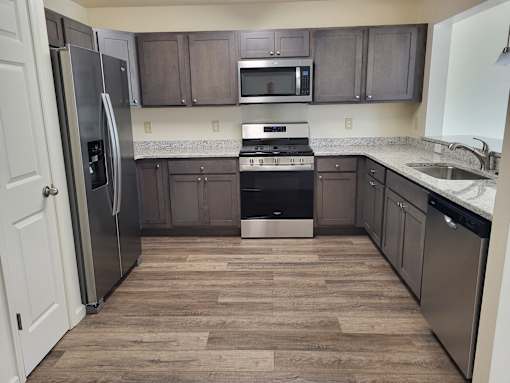 A kitchen with a refrigerator, oven, and microwave.