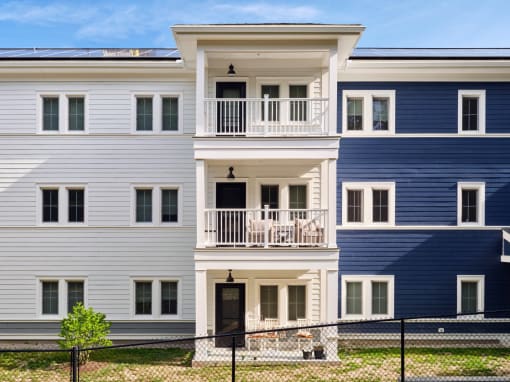a picture of a three story apartment building with blue and white siding and a black door