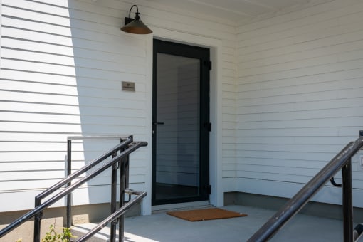 the front door of a white house with a black doorframe
