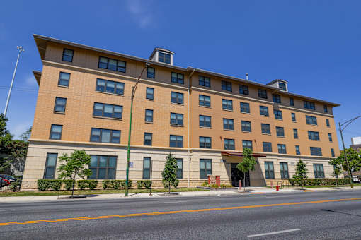 A large tan building with many windows sits on a street corner.