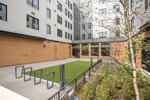 A courtyard with a green lawn and a brick wall.
