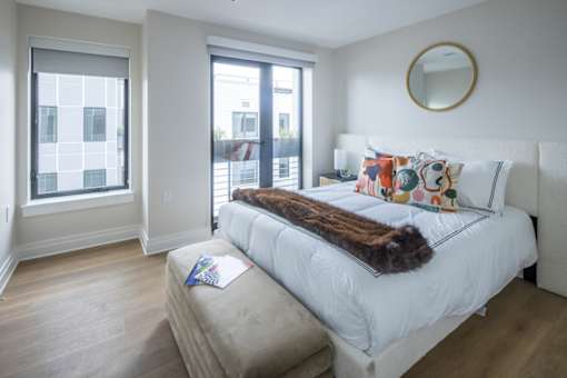 A bedroom with a large bed and a window overlooking a cityscape.