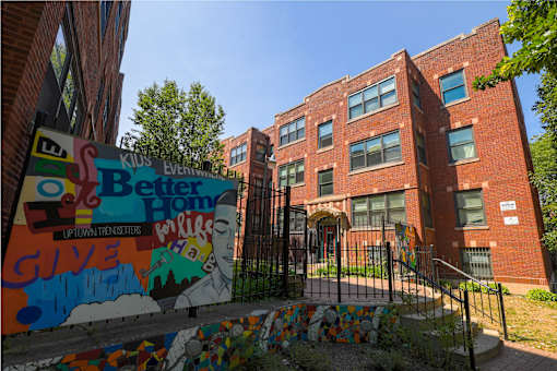 A brick building with a mural on the fence in front.