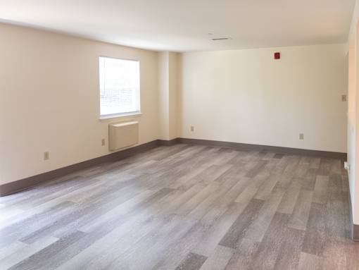 A room with a window and a wooden floor.