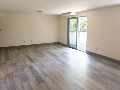A room with a sliding glass door and wood flooring.