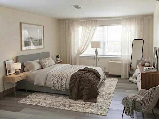 A bedroom with a large bed, a chair, and a nightstand.