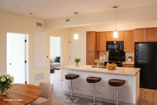 A kitchen with a black refrigerator, wooden cabinets, and a white island.