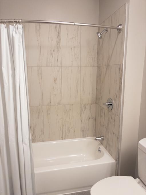 A white bathroom with a marble tile shower.