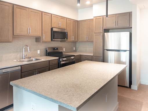 A kitchen with a refrigerator, sink, and microwave.