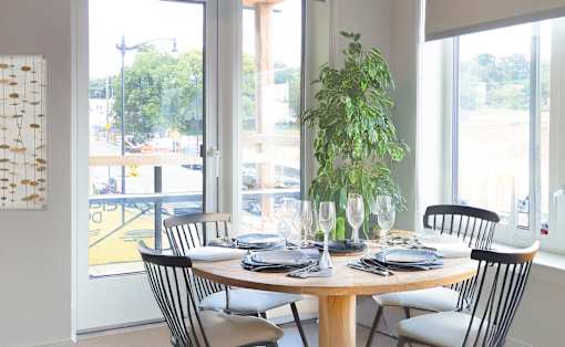 A dining table set with plates and glasses in front of a window.
